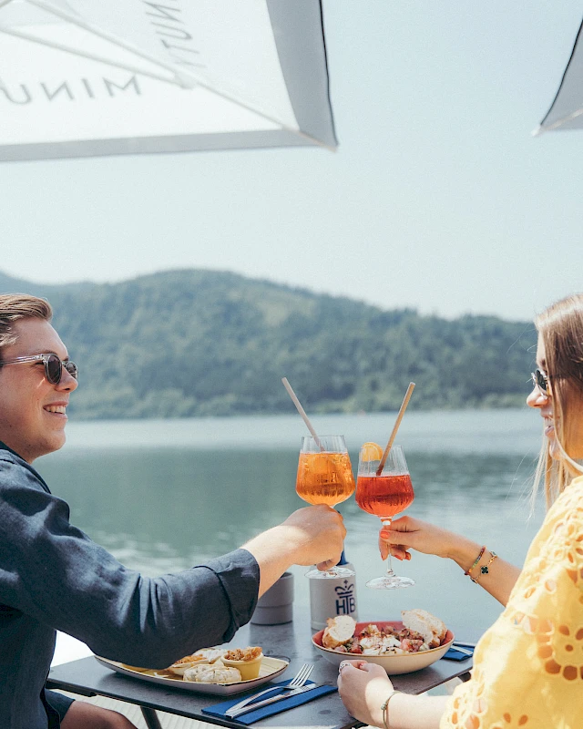 Paar stoßt an und genießt köstliches Essen bei Blick auf den Schliersee