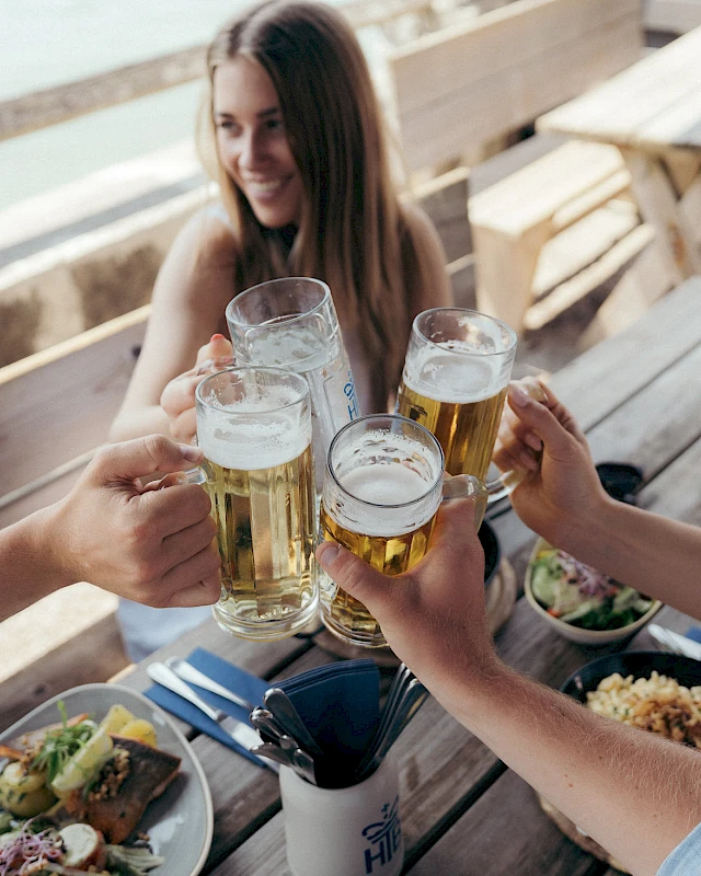 Freunde stoßen bei zünftigem Essen mit Bier im Biergarten an.