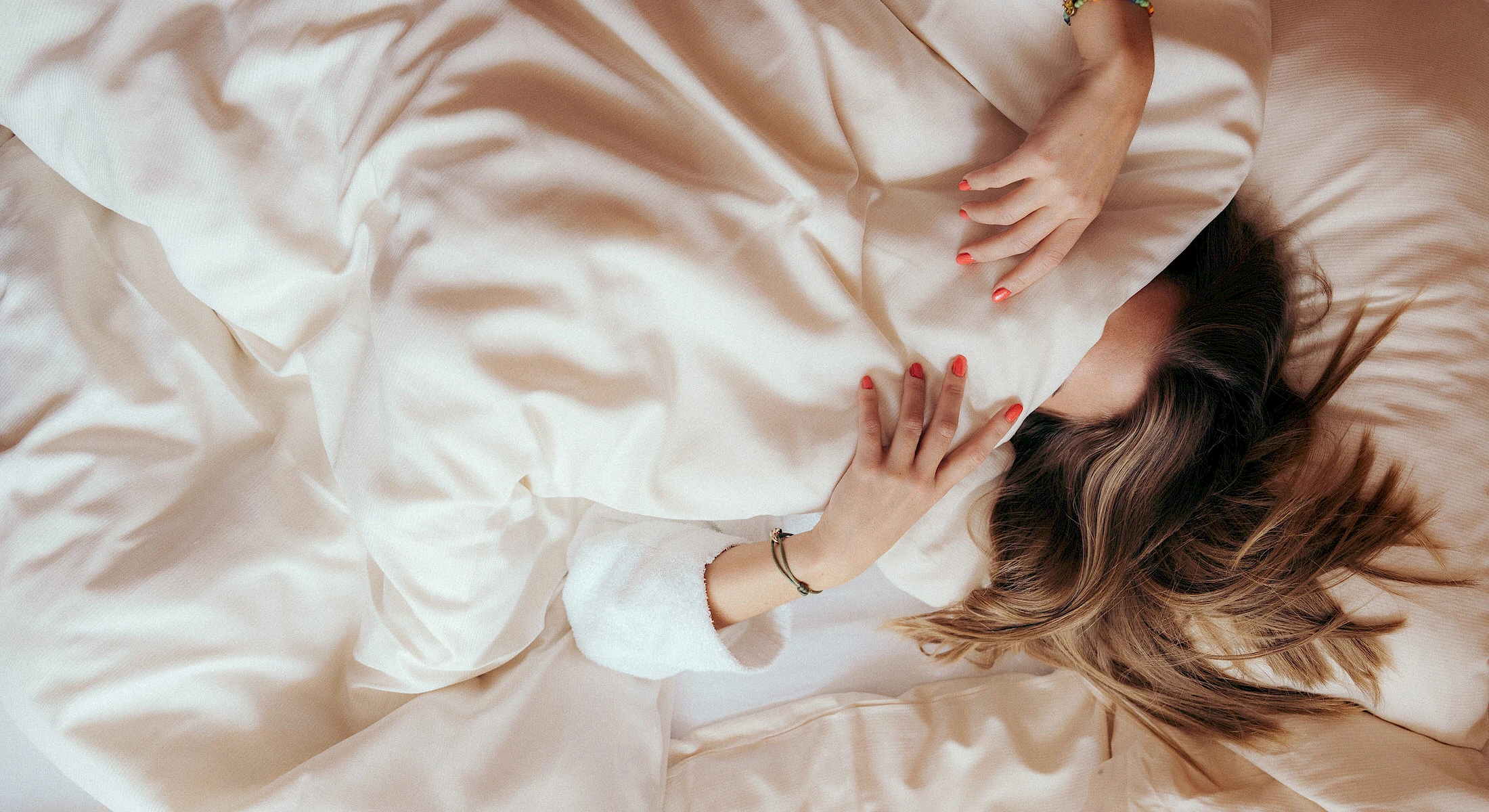 Frau in kuscheligem Bett in einem Zimmer im Schlierseer Hof